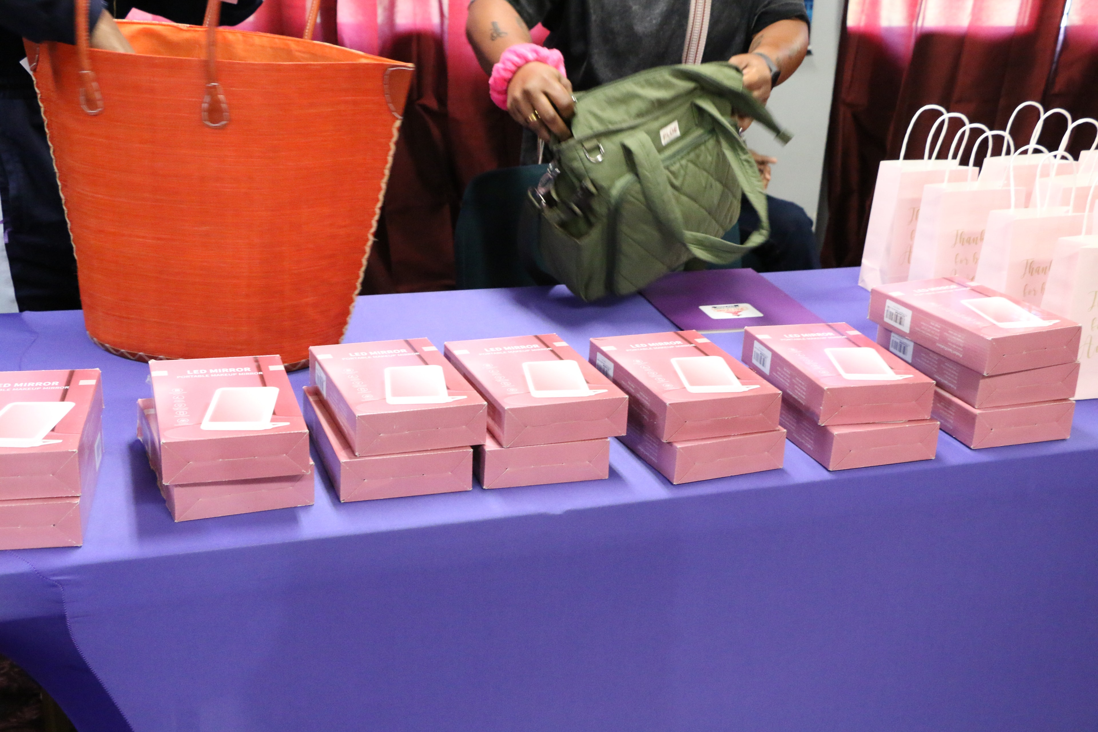 Pink LED mirror boxes and gift bags arranged on a vendor table